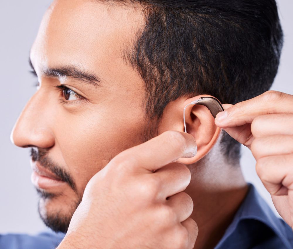 Deaf, cochlear and asian man ear in studio with hearing aid, audio and implant installation. Audiology, sound waves and face of Japanese guy with a disability, vibration or communication device.
